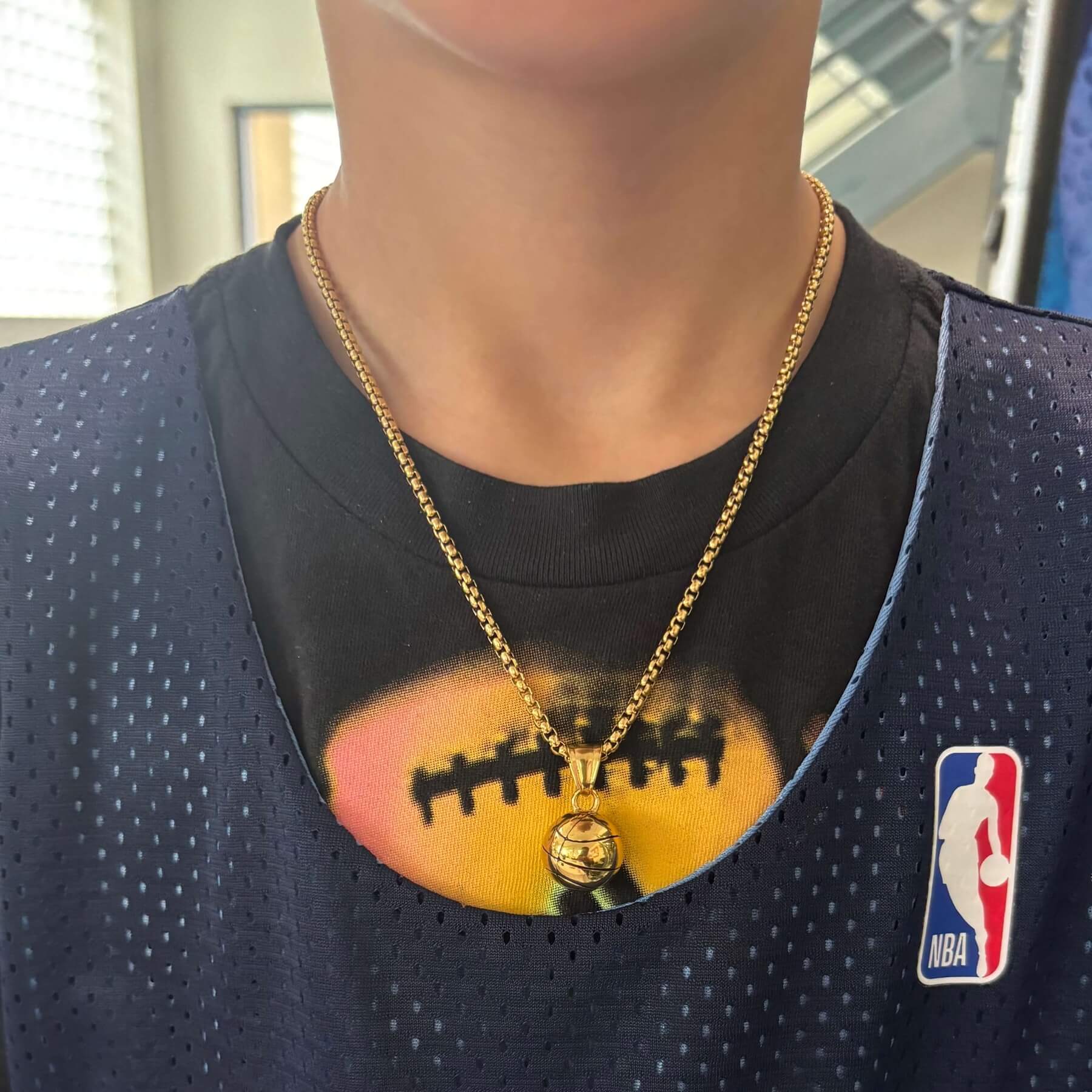 Gold plated 3D basketball pendant on a box chain necklace worn with a basketball jersey