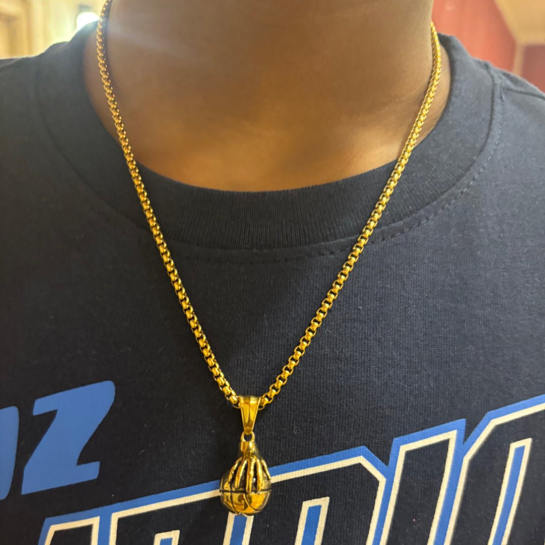 Gold plated hand palming basketball pendant on a 14k gold 3mm box chain necklace worn on a person
