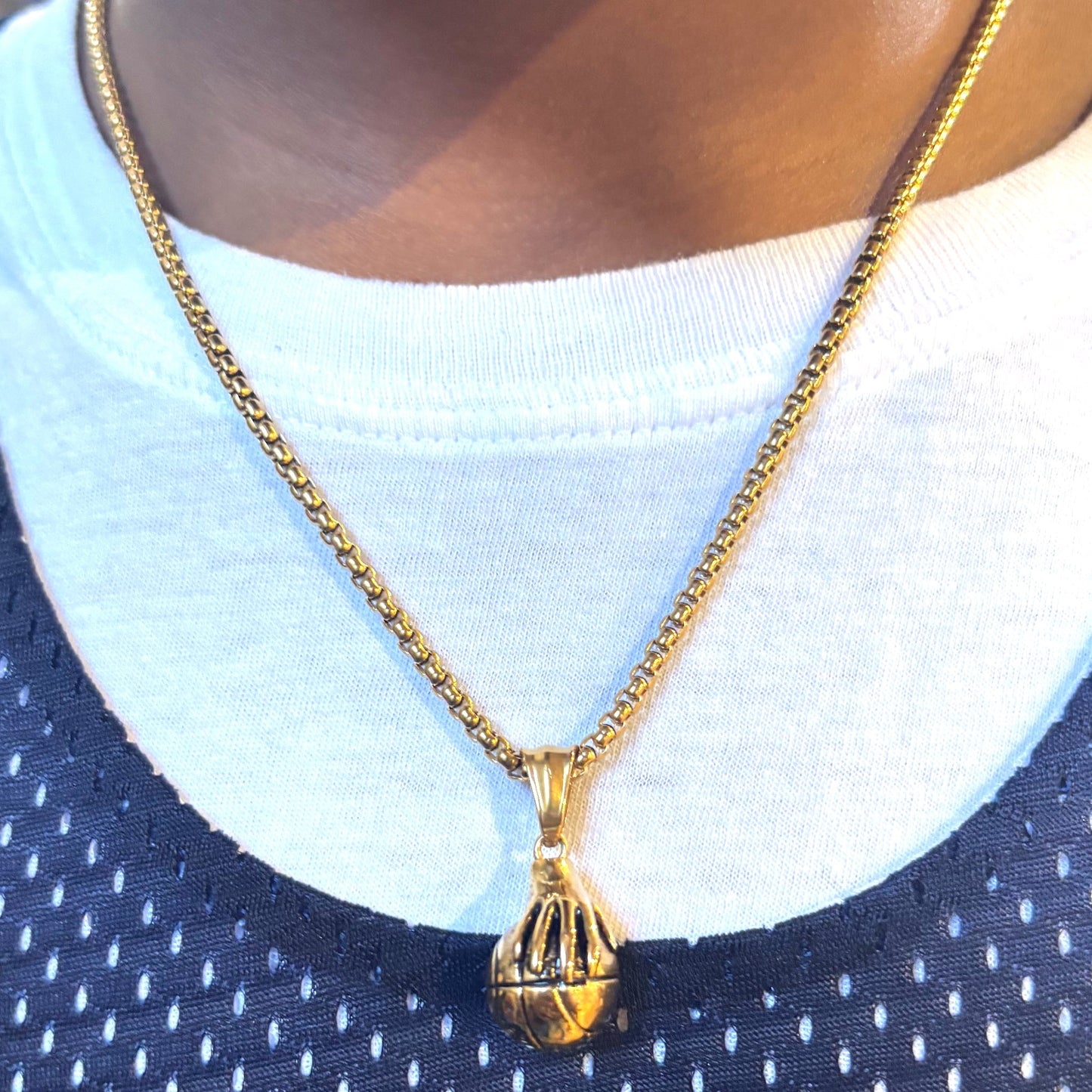 Gold plated hand palming basketball pendant necklace on box chain worn on person