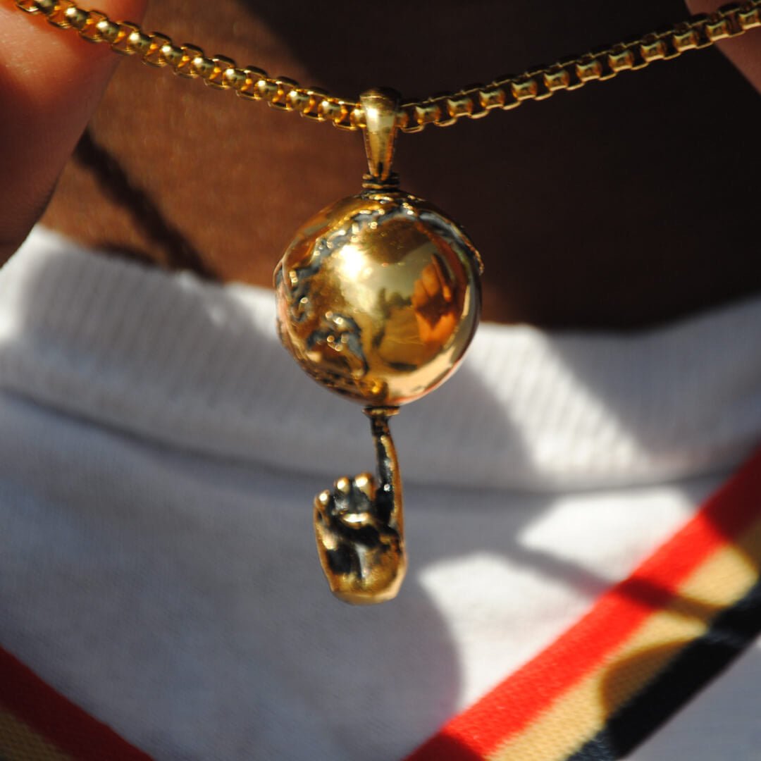 Gold spinning globe on finger basketball pendant with chain necklace in close-up view