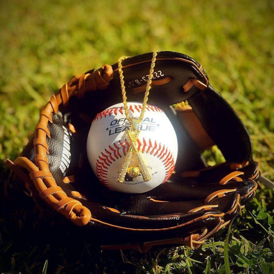 Gold plated studded baseball bats pendant with chain necklace displayed on baseball inside leather glove on grass