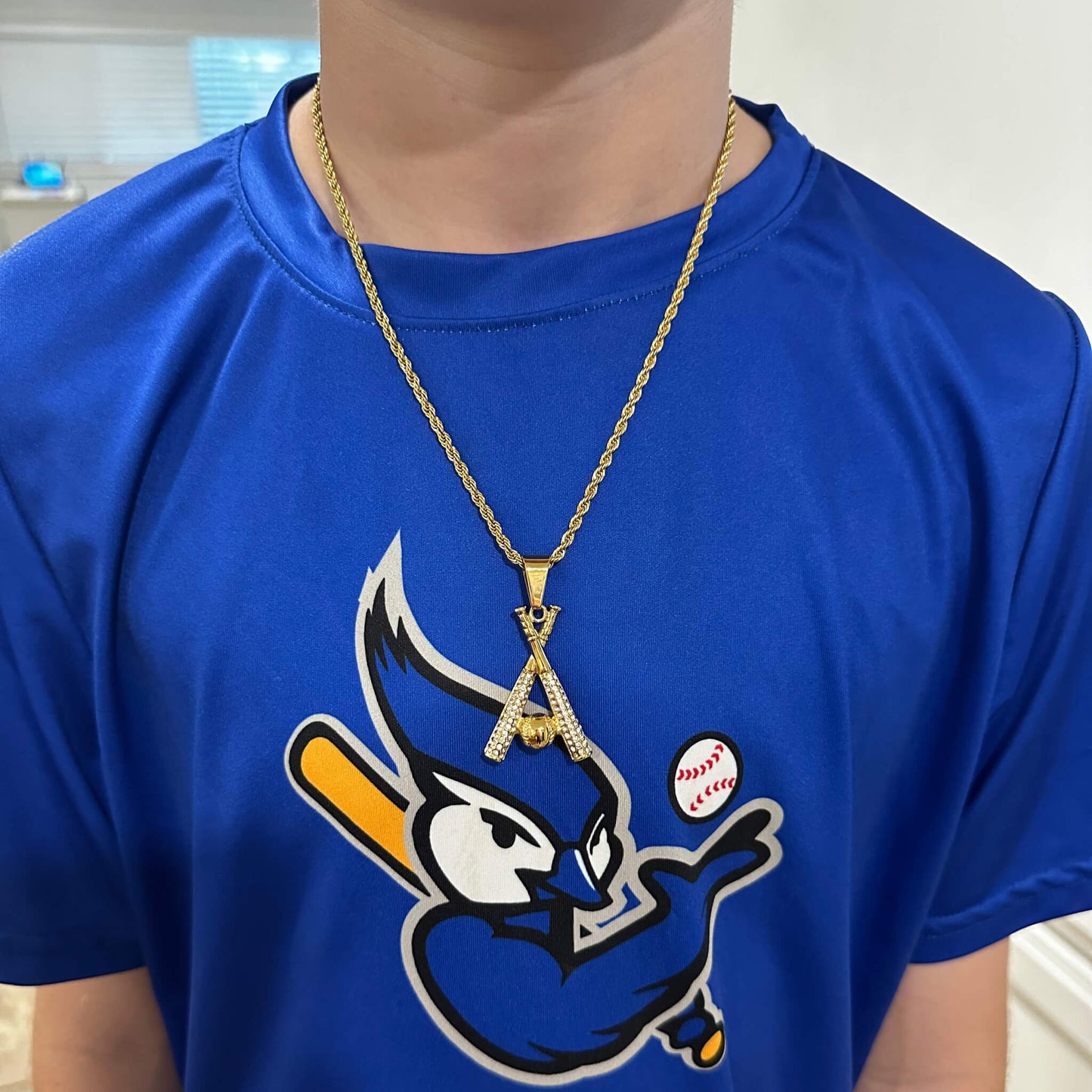 Gold-plated studded baseball bats pendant necklace on 3mm rope chain worn on blue baseball shirt