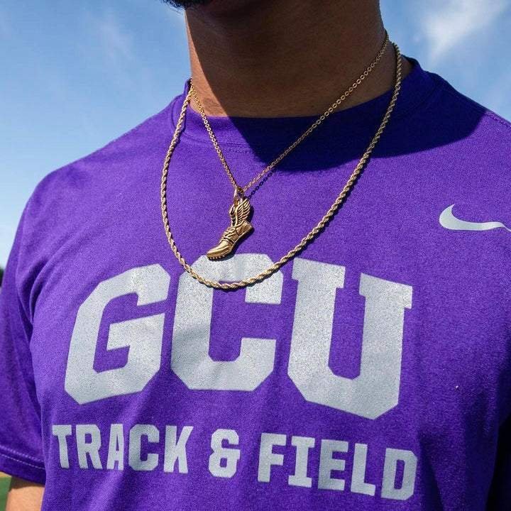 Gold winged running shoe pendant necklace worn over purple GCU Track & Field shirt