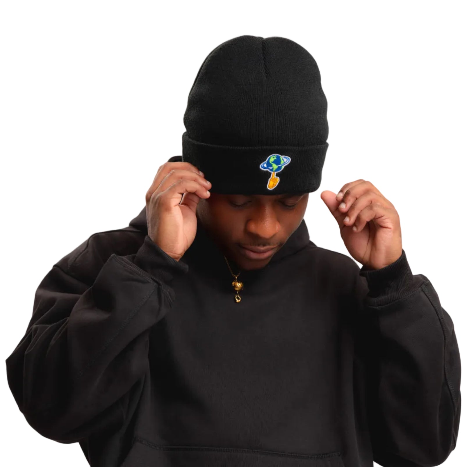 A man wearing a black knit beanie with a small colorful logo patch on the front, paired with a black zip-up hoodie, adjusting the beanie against a plain white background.