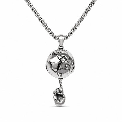 A silver-toned necklace featuring a detailed globe pendant that holds a small heart-shaped charm dangling below, set against a plain white background.